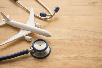 Airplane and stethoscope on wooden background with copy space. Going abroad for medical care. Medical tourism is when a person travels to another country for medical care. Healthcare, travel concept.