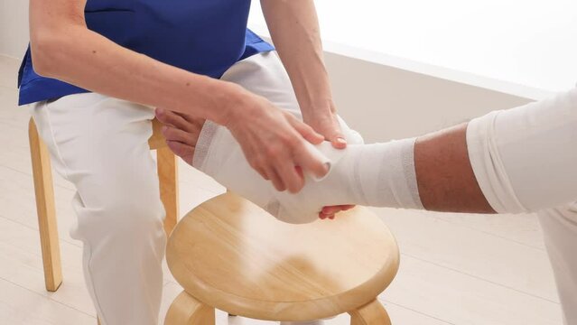 足首に包帯を巻く看護師　顔無し