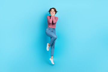 Full length portrait of cheerful lovely person hands touch cheeks jumping isolated on blue color background
