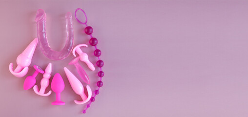 Pink silicone sex toys on a pink background. Erotic toy for fun. Diffrent anal butt plugs. Banner with space for text