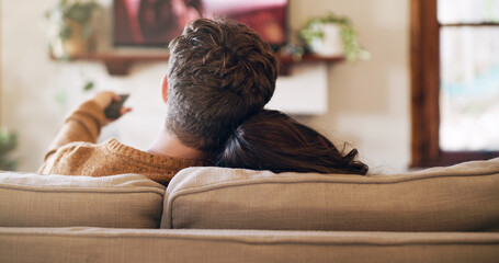 Watching tv, couple and love in a home on a living room sofa with bonding feeling relax. Cuddle,...