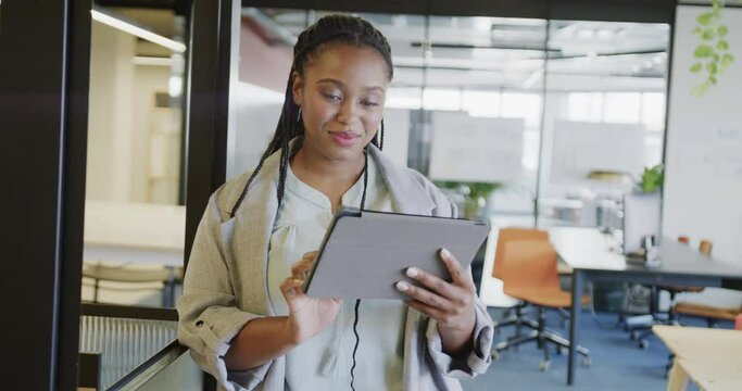 Happy african american casual businesswoman using tablet standing in office, in slow motion