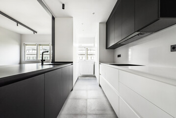 Kitchen furnished with a combination of black and white furniture without visible handles