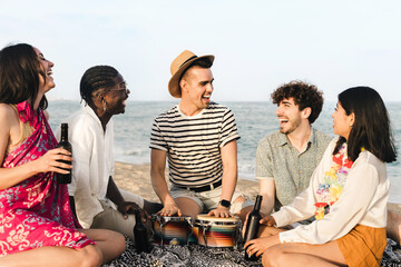 Group of multiracial friends playing music and singing on the beach