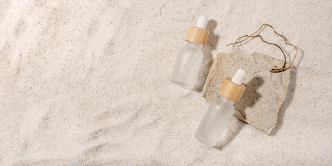 Glass bottles with a cosmetic product on a natural sandy background. Top view.