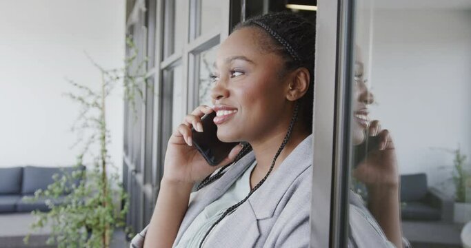 Happy african american casual businesswoman talking on smartphone in office lounge, slow motion