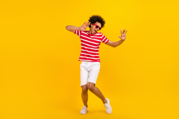 Fototapeta na wymiar Full length photo of funky cool man wear striped t-shirt dark spectacles having fun dancing isolated yellow color background