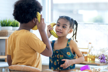 Cute little boy pretends to use a banana to talk on the smartphone, selective focus, boy and girl...