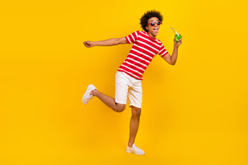 Fototapeta na wymiar Full length photo of pretty funky man wear striped t-shirt drinking cocktail having fun isolated yellow color background