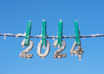 Background for New Year and Christmas cards, frozen and snow-covered symbols of 2024 hanging on a...