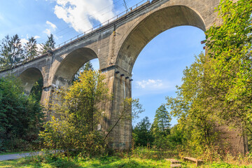 Concrete railway bridge over the Łabajów stream in the Głębce district in the tourist town of Wisła in the Silesian Beskids (Poland) on a sunny autumn day.