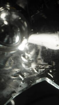Intriguing video captures a shattered cocktail glass resting on a black backdrop adorned with olives. Dolly slider extreme close-up. Vertical video.