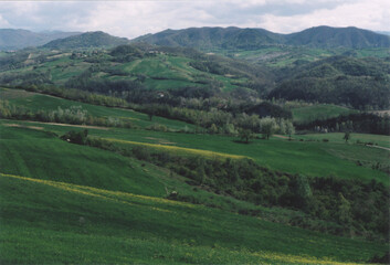 Fototapeta na wymiar Beautiful Hill Landscape with Clouds during Spring. Fortunago, Pavia Province, Italy. Film Photography