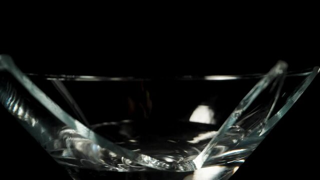 In the broken martini cocktail glass, an olive is falling, in slow motion, dolly slider.