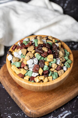 Colorful chocolate candy stones. Stone chocolate dragee in wooden bowl on dark background. Small multi-colored candies