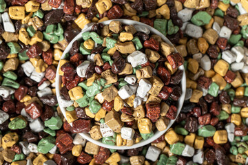 Colorful chocolate candy stones. Stone chocolate dragee in ceramic bowl. Small multi-colored candies. Top view