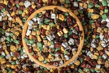Colorful chocolate candy stones. Stone chocolate dragee in wooden bowl. Small multi-colored candies. Top view