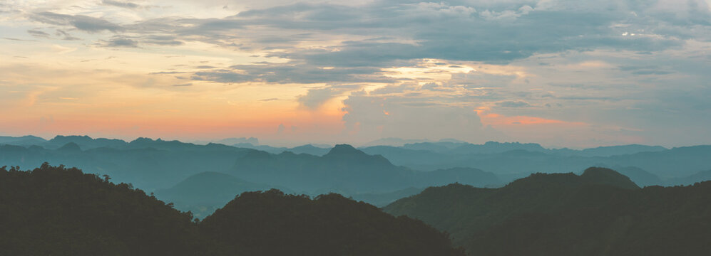 Panorama of Sunrise or sunset evening time over the mountains and forest with red or orange clouds sky. © Phongsak