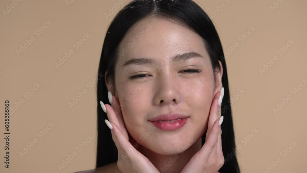 Wall mural Attractive young Asian woman posing at beige background