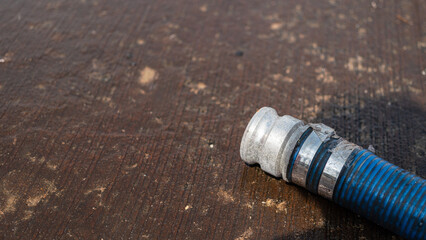 Head of water hydrant hose is laying down on wet cement ground. Industrial equipment object photo....