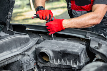 An auto mechanic opens the air filter housing of an internal combustion engine. Car repair