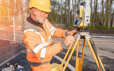 Site engineer setting his instrument during roadworks. Builder installing total positioning station...