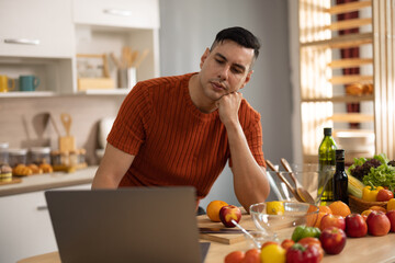 A homely and healthy male prepares nutritious diet, including variety of fruits. Following cooking show on laptop Mastery of peeling, chopping, and slicing fruits to prepare them in artistic style.