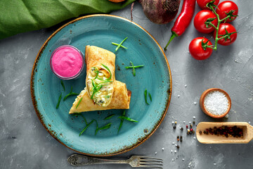 Pancake rolls stuffed with meat and sour cream in a clay bowl on a gray background. Blini, stuffed crepe