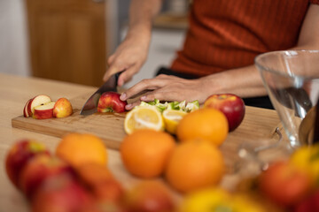 A homely and healthy male prepares nutritious diet, including variety of fruits. Following cooking show on laptop Mastery of peeling, chopping, and slicing fruits to prepare them in artistic style.