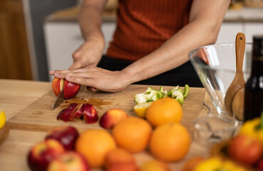 A homely and healthy male prepares nutritious diet, including variety of fruits. Following cooking show on laptop Mastery of peeling, chopping, and slicing fruits to prepare them in artistic style.