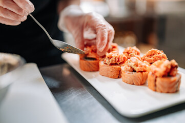 professional chef's hands making sushi roll in a restaurant kitchen