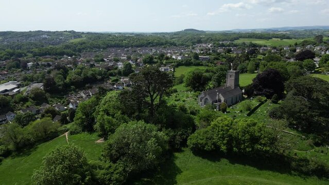 Highweek, Newton Abbot, South Devon, England: DRONE AERIAL VIEWS: The drone flies r-to-l showing Highweek village with All Saints Church in the foreground. In the distance is Dartmoor National Park.