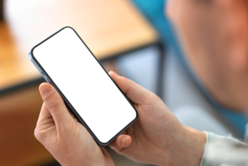 Man using smartphone with blank screen and frameless modern design while sitting on the sofa in home interior