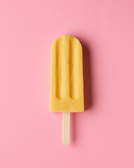 Yellow fruit popsicle on pink background