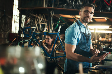 Portrait, calculator and repair man in bicycle shop working in store for sales. Face, bike mechanic and serious male professional from Canada with glasses, pride and mature in cycling workshop.