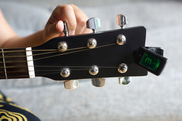 Selected focus photo of someone tuning guitar with digital guitar tuner.                   