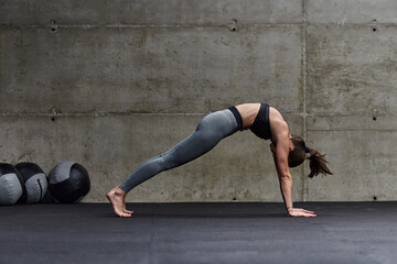 Fit woman in a modern gym working flexibility and strength through various exercises, demonstrating...