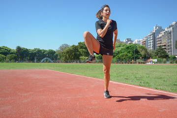 young latin woman training raising her leg bent to the side rotating the hip joint