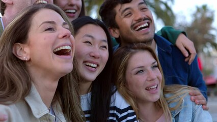 Happy young group of student friends laughing together outdoors. Multiethnic millennial people having fun enjoying day off in city street. Social meeting and youth community concept.