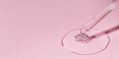 Facial serum banner. Drop of cosmetic serum or oil with bubbles pouring from pipette on pink background. Beauty product advertising. Liquid gel with retinol closeup. Front view, copy space.