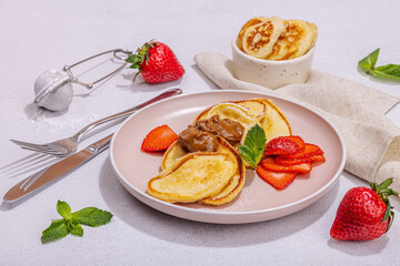 Cottage cheese pancakes, syrniki, curd fritters with strawberry, mint and powdered sugar on plate