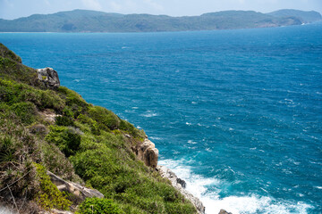 a peaceful Con Dao island, Vietnam is a Vietnamese island heaven. Coastal view with waves, coastline, clear sky and road, blue sea, tourists and mountain