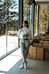 Pretty woman in a white shirt and glasses posing against the backdrop of a modern mountain hotel.Businessman woman concept