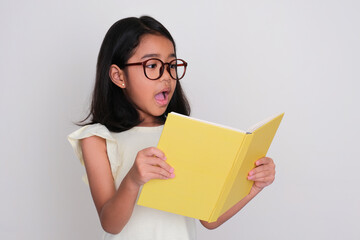 Asian little girl showing surprised expression when reading a book