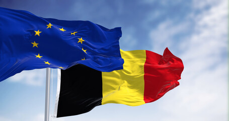 Belgium and European Union flags waving together on a clear day