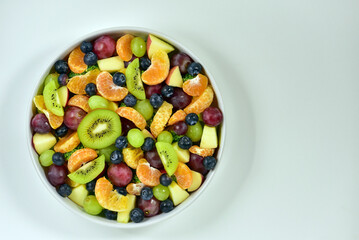 Healthy fresh fruit salad bowl on white background. Top view. Healthy food concept, healthy high vitamin fruit, mixed fruit background.