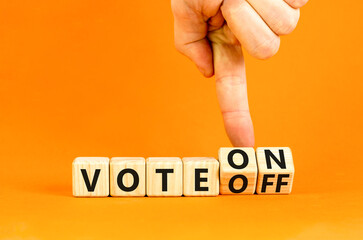 Vote on or off symbol. Businessman turns wooden cubes and changes word Vote off to Vote on. Beautiful orange table orange background. Business and vote on or off concept. Copy space.