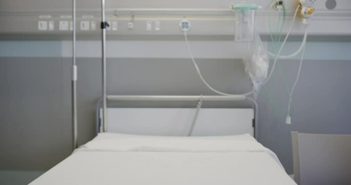 Rack focus shot of empty hospital bed with drip and stands in hospital ward, slow motion