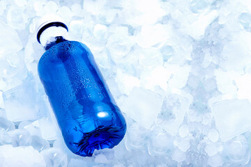 Blue water bottle in very cold ice cubes horizontal