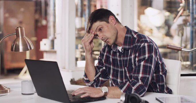 Mental health, man business owner with laptop and headache at desk in his office at work with metalwork. Stress or anxiety, technology or connectivity and male person sitting with writing an email